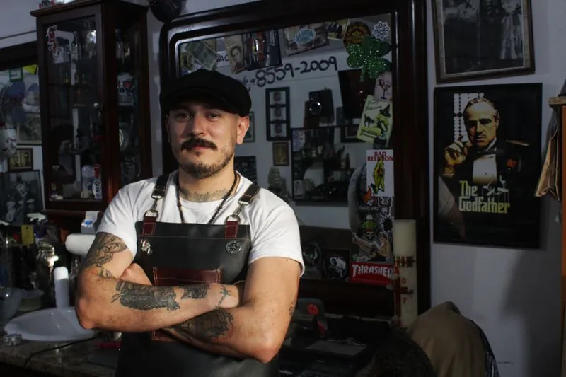 A barber in a leather apron standing with arms folded