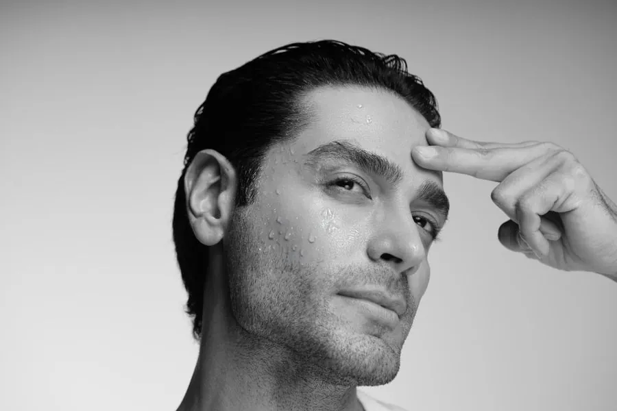 Black and white portrait of a man with slicked hair touching his temple