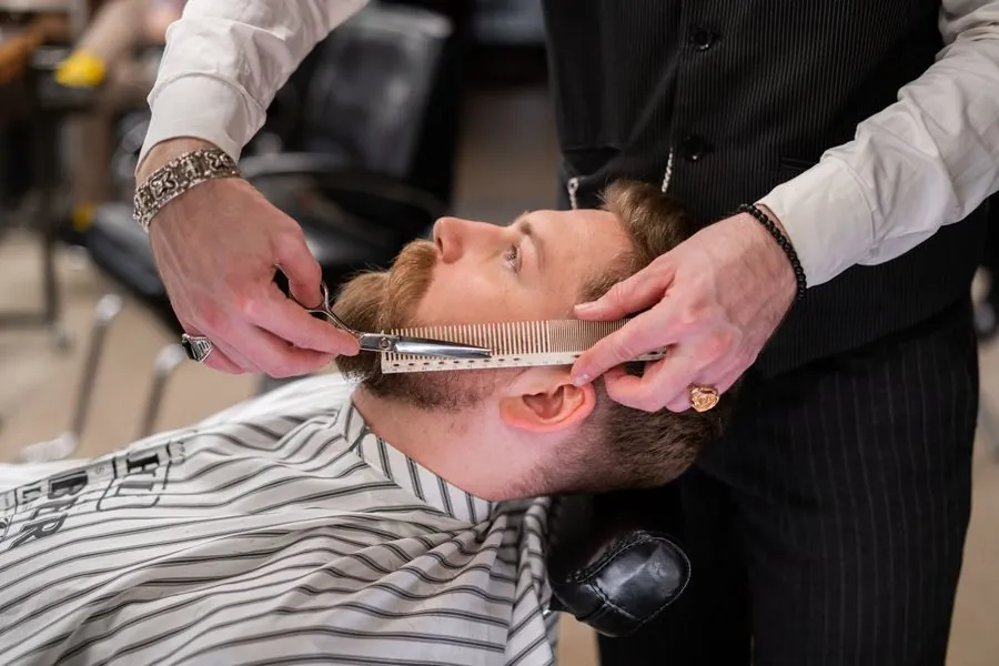A barber combing a customer's beard with care
