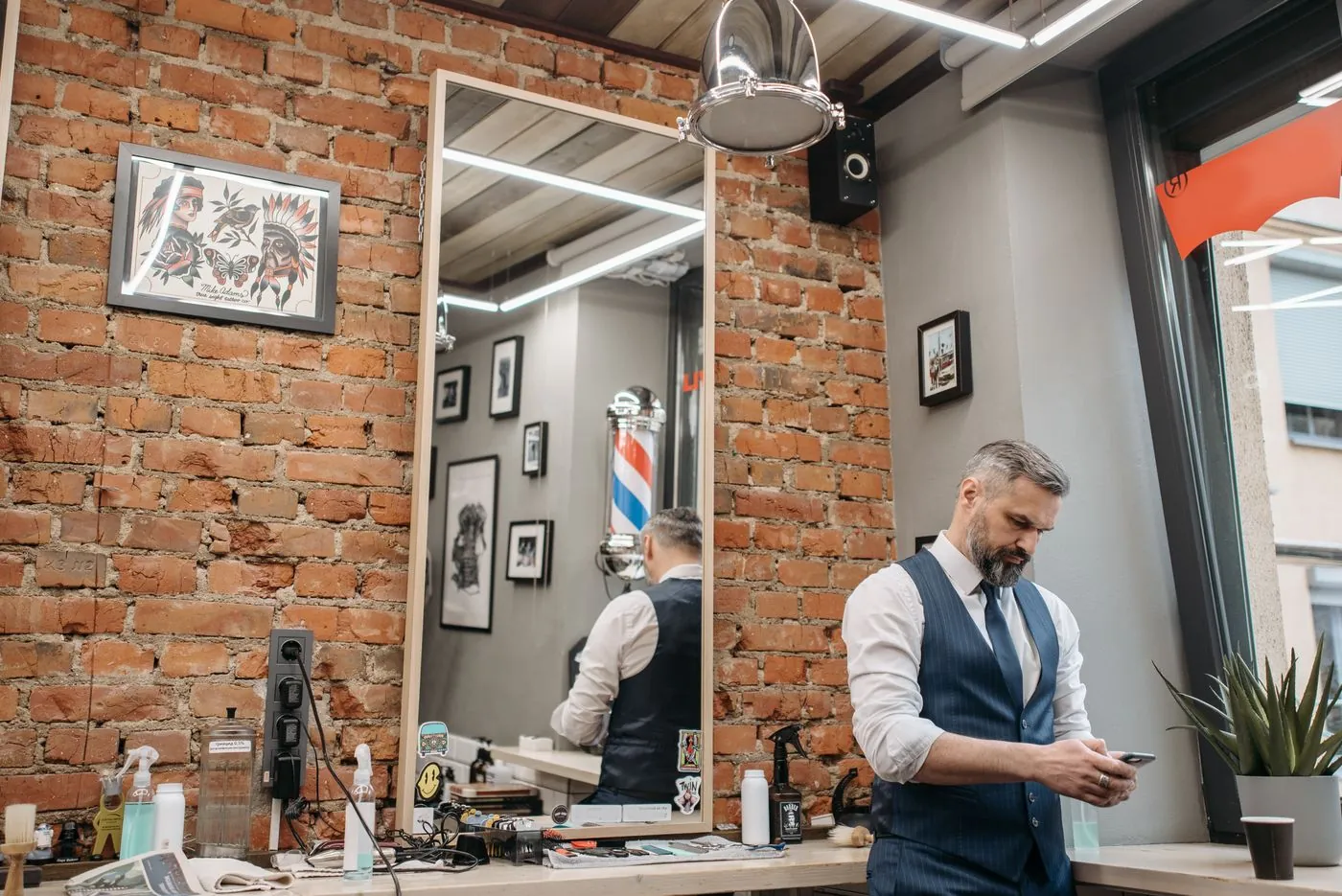 A barber at work in a brick-walled shop with a striped pole